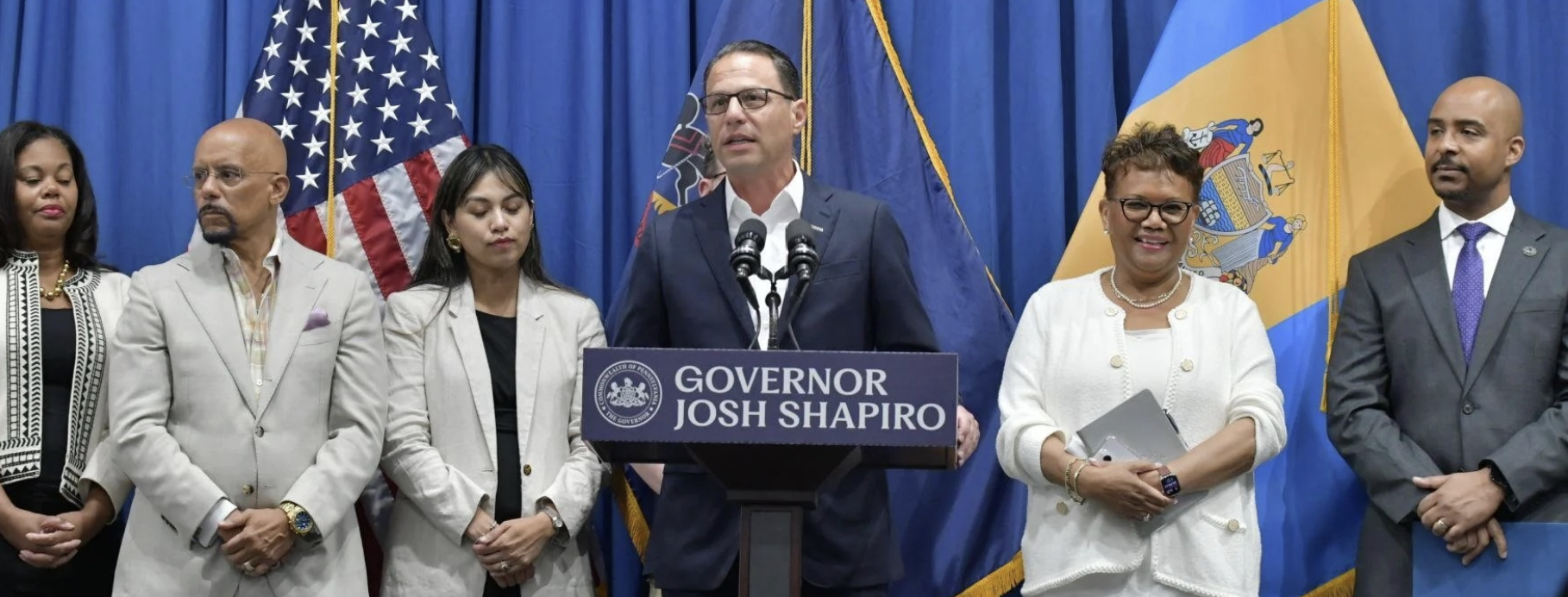 Gov. Josh Shapiro (at podium) speaks about his executive order signed Tuesday to help African American and other small, diverse firms get state contracts. (l-to-r) Regina Hairston, president of the African American Chamber of Commerce; State Sen. Vincent Hughes, D-7th District; Somaly Osteen, of the Asian American Chamber of Commerce of Greater Philadelphia; Della Clark, president of The Enterprise Center and Reggie McNeill, secretary of the Department of General Services. 